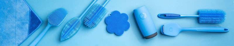 Blaue Tierpflegeartikel, Bürsten und eine Fusselrolle, ordentlich angeordnet auf hellblauem Hintergrund.