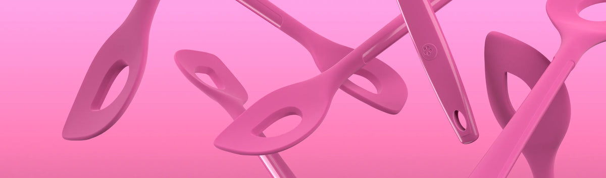 Vor einem rosa Farbverlauf schweben mehrere rosa Küchenutensilien mit ovalen Löchern.
