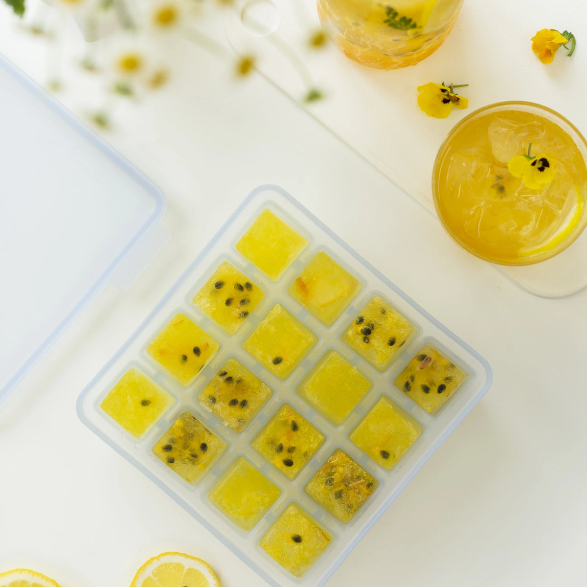 Mit der Eiswürfelform von Kochblume GmbH lassen sich leuchtend gelbe Fruchteiswürfel herstellen, die sich ideal als Beilage zu Getränken eignen, die mit Zitronenscheiben und leuchtend gelben Blüten garniert sind. Diese farbenfrohen Eiswürfel werten nicht nur die Präsentation Ihrer Sommergetränke auf, sondern verleihen jedem Schluck auch einen erfrischenden Hauch von Zitrusaroma.