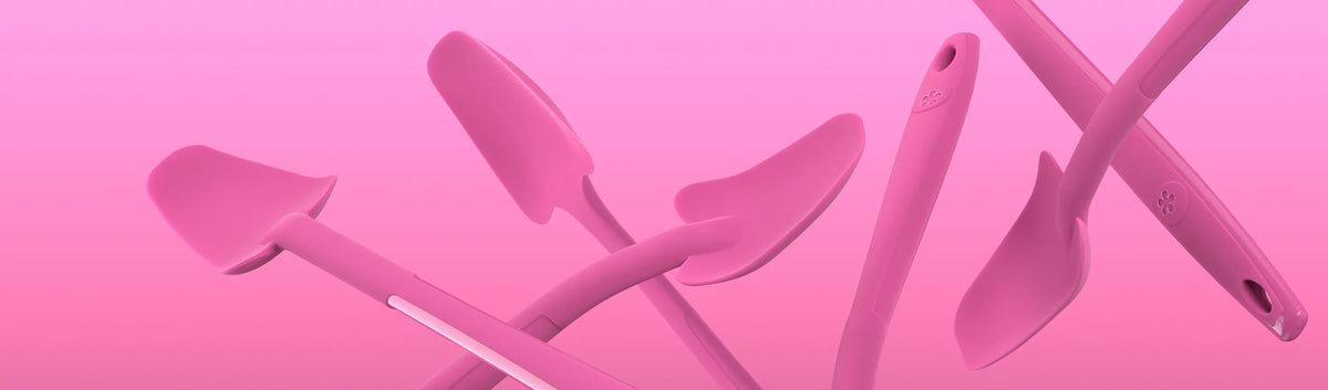 Auf einem rosa Hintergrund mit Farbverlauf schweben mehrere rosa Küchenspatel.