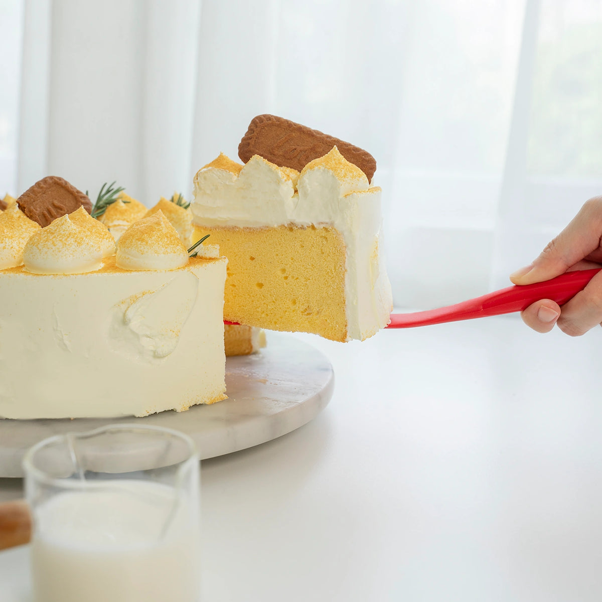 Eine Hand serviert ein Stück Kuchen mit Sahne und Keksen, das mit dem Spatel der Kochblume GmbH angerichtet wurde; daneben steht ein Glas Milch – die perfekte Kulisse für alle, die detaillierte Produktbeschreibungen mit echtem Inhalt statt nur CSS-Code suchen.