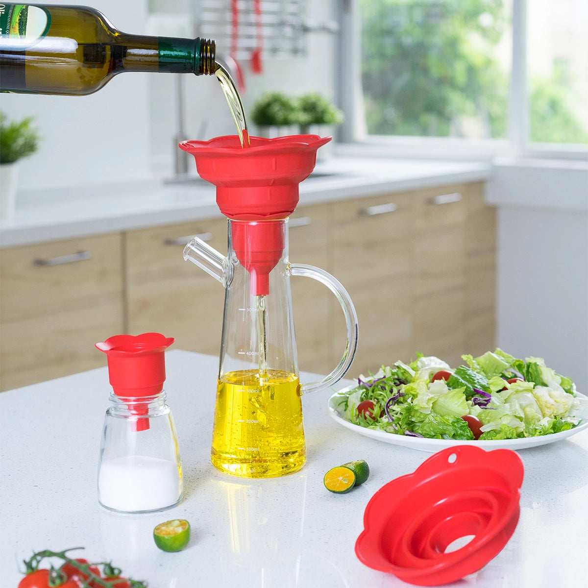 Mit dem „Falttrichter“ der Kochblume GmbH wird Olivenöl in einer hellen Küche, umgeben von frischem Salat und Salz, in eine Glasflasche mit dem leuchtend roten Trichter gegossen – die perfekte Kulisse, um Ihre kulinarischen Kreationen zu veredeln.