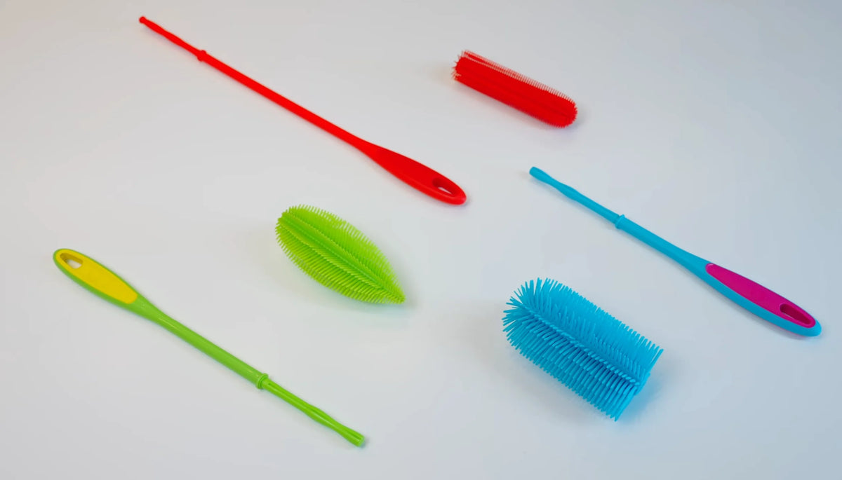 Sechs bunte Flaschenbürsten und Bürstenköpfe aus Silikon, angeordnet auf einem weißen Hintergrund.