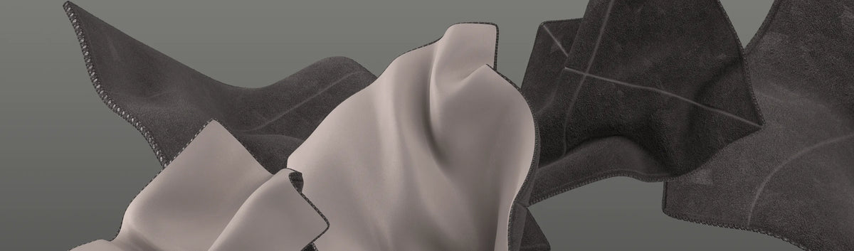 Abstrakte Formen aus hellbraunen und schwarzen Stoffstücken mit sichtbaren Nähten auf einem einfarbigen grauen Hintergrund.